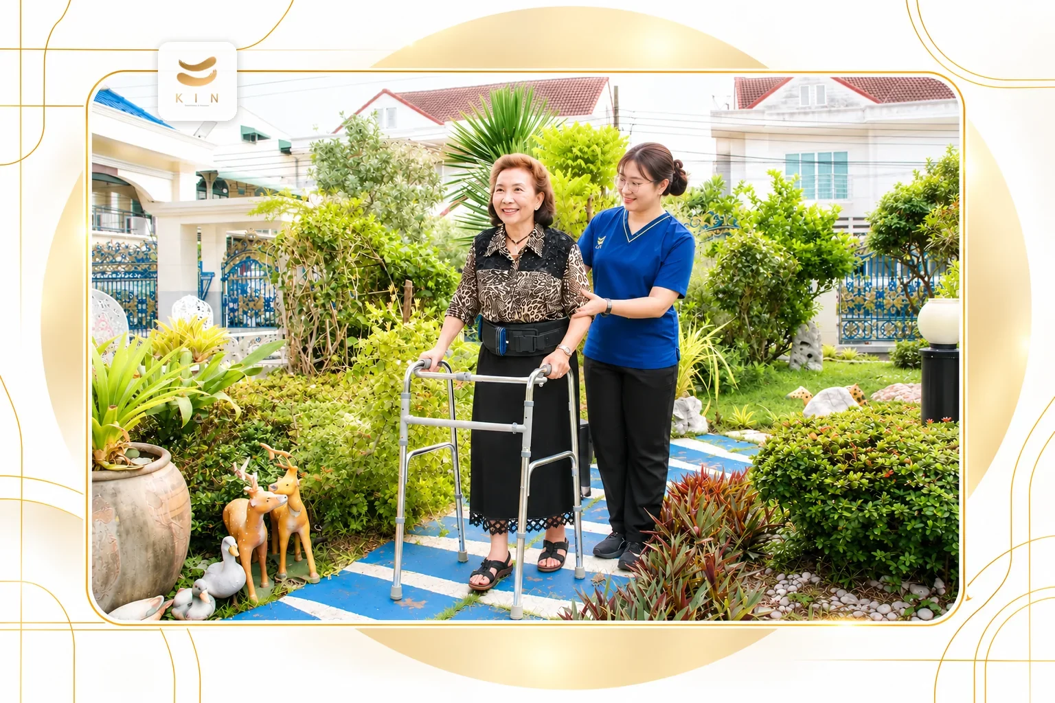 นักกายภาพบำบัดชุดน้ำเงินฝึกเดินผู้สูงอายุด้วยวอล์คเกอร์ในสวน KIN HomeCare physiotherapist gait training ศูนย์ฟื้นฟูคิน KIN