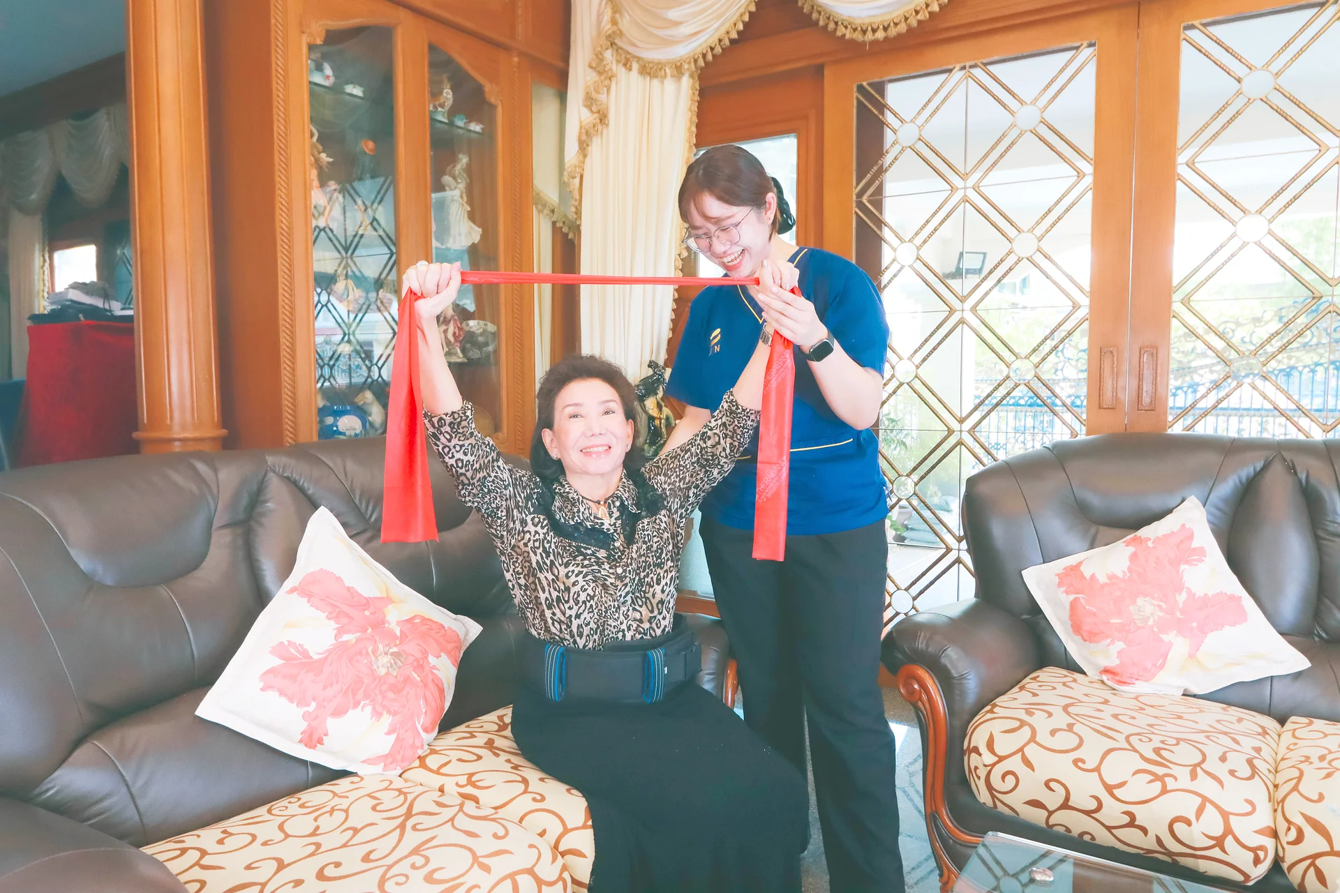 KIN physical therapist training the affected arm of a stroke patient at home with a resistance band